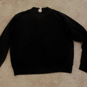 Svart tröja från H&M - Säljer en klassisk svart tröja från H&M Basics. Perfekt för en stilren look med rund hals och långa ärmar. Passar till alla tillfällen och är lätt att matcha med andra plagg.