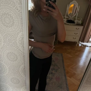 Beige ärmlös topp - Snygg beige ärmlös topp med draperad halsringning. Perfekt för en stilren och enkel look.