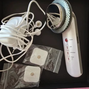 Vit ultraljudsapparat med sladdar - Säljer en vit ultraljudsapparat med flera funktioner som EMS, infraröd och sonic. Inkluderar sladdar och två självhäftande elektroder. Perfekt för hudvård och massage.
