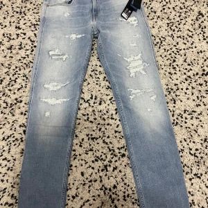 Ljusa jeans från Replay - Snygga ljusa jeans från Replay med slitna detaljer och en klassisk femficksdesign. De har en dragkedja och knapp framtill. Perfekta för en avslappnad stil.