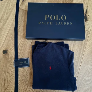 Mörkblå tröja från Polo Ralph Lauren - Säljer en stilren svart tröja från Polo Ralph Lauren med det klassiska röda logotypbroderiet på bröstet. Tröjan har långa ärmar och är perfekt för en avslappnad men elegant look. Levereras i originalförpackning.