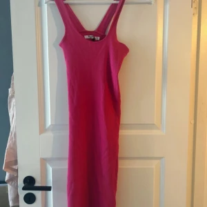 Rosa ribbad klänning - Snygg rosa ribbad klänning med breda axelband. Perfekt för en somrig look. Klänningen har en enkel och stilren design som passar till många tillfällen.