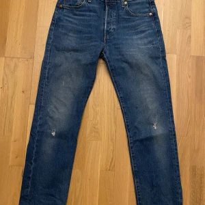 Levis 501 jeans - Klassiska Levis 501 jeans i blå denim med en rak passform. De har en knappgylf och fem fickor. Perfekta för en avslappnad stil.