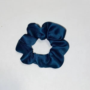 Mörkblå satin scrunchie - Snygg och elegant mörkblå scrunchie i satin som ger en lyxig touch till din frisyr. Perfekt för både vardag och fest, och kan även bäras som ett armband för en stilfull look. !OBS den i håret är en annan än den som säljs den som bild 1 och 3 har den som säljs!