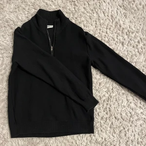Svart half zip  - Jag säljer en väldigt snygg half zip tröja från Solid. Den är nästan helt ny, endast använd en gång. Stilren svart halfzip som passar till både skola och utekväll. Hör av er vid minsta fråga!