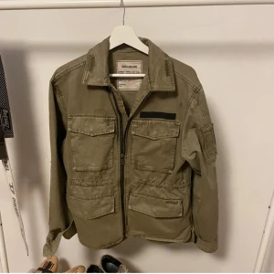 Beige jacka från Zadig & Voltaire - Snygg beige jacka från Zadig & Voltaire med dragkedja och flera praktiska fickor. Perfekt för en avslappnad stil. Jackan har en klassisk krage och långa ärmar. Pris inte hugget i sten!