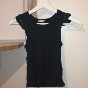 Svart ärmlös topp från C - Snygg svart ärmlös topp från C i storlek 146/152. Perfekt för varma dagar eller som ett lager under en jacka. Enkel och stilren design som passar till det mesta.