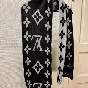 Svart och grå halsduk från Louis Vuitton - Ikonisk och elegant svart/grå halsduk från Louis Vuitton med odödliga monogrammönster. Perfekt accessoar. Vändbar med kontrasterande färger på varje sida. Nyskick.