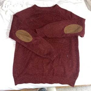 Vinröd tröja från Cedar Wood State - Säljer åt pojkvän.  E vinröd tröja från Cedar Wood State med bruna armbågslappar. Tröjan har en klassisk passform och är perfekt för kyligare dagar. Den är tillverkad i ett mjukt material och har ribbade muddar vid ärmslut och nederkant.