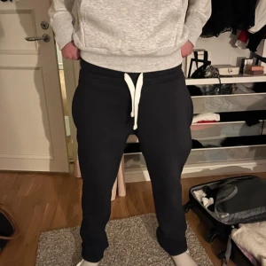 Mörkblå mjukisbyxor från Russell Athletic - Säljer ett par helt nya mörkblå stilrena mjukisbyxor från det välkända varumärket Russemerch. Byxorna har en bekväm passform med snörning i midjan och är perfekta för en avslappnad stil. De är tillverkade i mjukt material och har elastiska muddar vid bensluten.