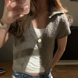 Brun stickad kofta från Zara - Säljer en mysig brun stickad kofta från Zara. Den har korta ärmar och en knapp framtill. Perfekt för lager-på-lager och ger en avslappnad look. 🧶