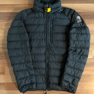 Svart dunjacka från Parajumpers - Snygg och funktionell svart dunjacka från Parajumpers med dragkedja och hög krage. Jackan har en quiltad design och en praktisk bröstficka med dragkedja. Perfekt för kyligare dagar. Har kvitto och är köpt i danmark. Liten prick på axeln syns nästan inte alls. Syns på sista bilden.