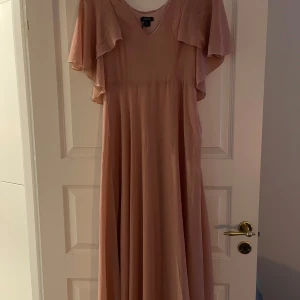 Rosa långklänning från Boohoo - Elegant rosa långklänning från Boohoo med v-ringad design och fladdriga kortärmar. Hade tänkt ha den som balklänning men köpte en annan. Så den är aldrig använd.