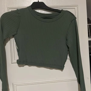 Grön ribbad croppad tröja från Even&Odd - Säljer en stilren grön ribbad tröja från Even&Odd. Tröjan är croppad med långa ärmar och har en enkel design som passar perfekt till vardags. Perfekt för lager-på-lager-stil eller som statement-plagg.