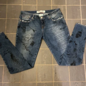 Blå jeans med tryck från MET - Snygga blå jeans från MET med unikt tryck över hela byxorna. De har en tight passform och klassisk femficksdesign. 