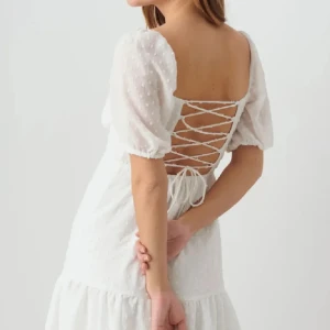 Vit klänning med snörning - Jättesöt vit kortklänning med puffiga kortärmar och snörning i ryggen. Klänningen har en söt volangdetalj nedtill och ett diskret prickigt mönster. Köptes till studenten men kom aldrig till användning, så den är endast provad! 