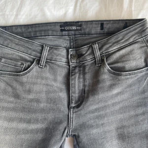 Grå jeans från Guess - Snygga grå jeans från Guess. Dom är sydda bootcut men inget som syns då det är i samma färg! 