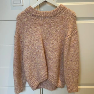 Stickad tröja från Vero Moda - Mysig stickad tröja från Vero Moda med en melerad look i rosa och gul. Tröjan har långa ärmar och en ribbad krage som ger en avslappnad stil. Otroligt fin och blir en fin touch till outfiten. Säljer en likadan fast i en blå/lila ton kika den också! 