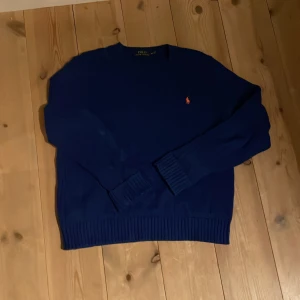  Ralph Lauren cableknit - Tvär fet blå kabelstickad tröja från Ralph Lauren med det klassiska logotypbroderiet i röd på bröstet. 