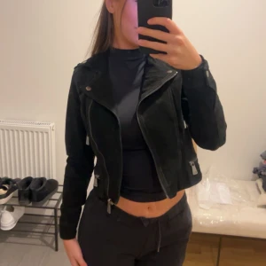 Svart mocka jacka - Snygg svart mockajacka med dragkedja. Jackan har en croppad passform och är perfekt för en cool look. Äkta mocka aldrig använd