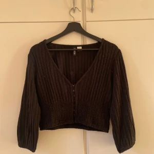 Svart ribbad kofta från H&M - Säljer en svart ribbad kofta från H&M med dragkedja framtill. Koftan har långa ärmar och en croppad passform, perfekt för lager på lager-stil. Passar både till vardags och mer uppklädda tillfällen. Aldrig använd!