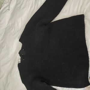 Overzied Svart tröja med rosett. FINNS ÄVEN I VIT FÄRG I STORLEK L.  - Snygg svart tröja med en dekorativ rosett vid ryggen. Tröjan har långa ärmar och är perfekt för kyligare dagar. Enkel och stilren design som passar till många olika outfits.