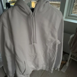 Vit hoodie från H&M - Säljer en vit hoodie från H&M i storlek M. Den har en klassisk design med känguruficka och justerbar huva. Perfekt för en avslappnad stil.