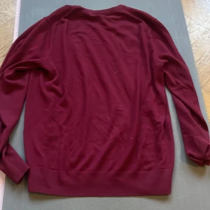 Vinröd tröja från Uniqlo - Säljer en stilren vinröd tröja från Uniqlo. Perfekt för kyligare dagar med sin mjuka och bekväma passform. Tröjan har långa ärmar och en enkel design som gör den lätt att matcha med olika outfits.