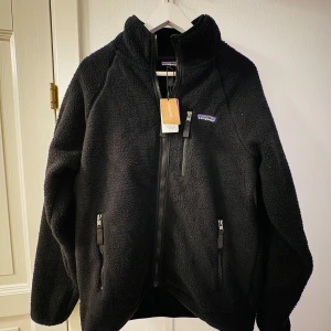 Patagonia fleece - Säljer en svart fleece från Patagonia pga aldrig använt den. Helt ny med etiketten kvar.                                   Storlek L men passar bra också på M. Håller dig varm under kyliga vinterdagar och är perfect för skidor och klättrning. Ord pris 1699kr, mitt pris 1099kr.           Pris kan diskuteras vid snabb affärr