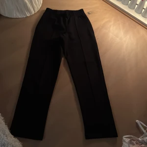 Svarta byxor med resårmidja - Snygga svarta byxor med resårmidja för en bekväm passform. Byxorna har en rak stil och är perfekta för en stilren look. De är tillverkade i ett mjukt material som ger en skön känsla hela dagen.