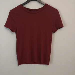 Vinröd t-shirt från Bik Bok - Säljer en stilren vinröd t-shirt från Bik Bok i storlek XS. T-shirten har en klassisk rund hals och korta ärmar, perfekt för en avslappnad look.