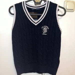 Mörkblå stickad väst från Brandy Melville - Snygg mörkblå stickad väst från Brandy Melville med vit broderad text . V-ringad design, helt ny med prislapp ENDAST testad. One size, passar XS. Säljer pga jag inte hann returnera.