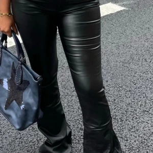 Svarta skinnbyxor - Snygga svarta skinnbyxor med bootcut-stil. Perfekta för en trendig look med en tight passform upptill och utsvängda ben. Byxorna har en klassisk design med fickor bak och en slät framsida.