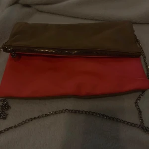 Rosa och brun axelväska med kedja - Snygg axelväska i rosa och brunt med en stilren kedja som axelrem. Väskan har en praktisk dragkedja och knappstängning för säker förvaring. Perfekt för att ge en färgklick till din outfit.🤎