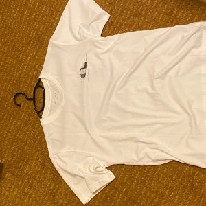Vit t-shirt  - Säljer en vit t-shirt från Uniqlo med ett coolt tryck på baksidan i blått och svart. T-shirten är kortärmad och tillverkad i bomull, aldrig använd då den var för liten 