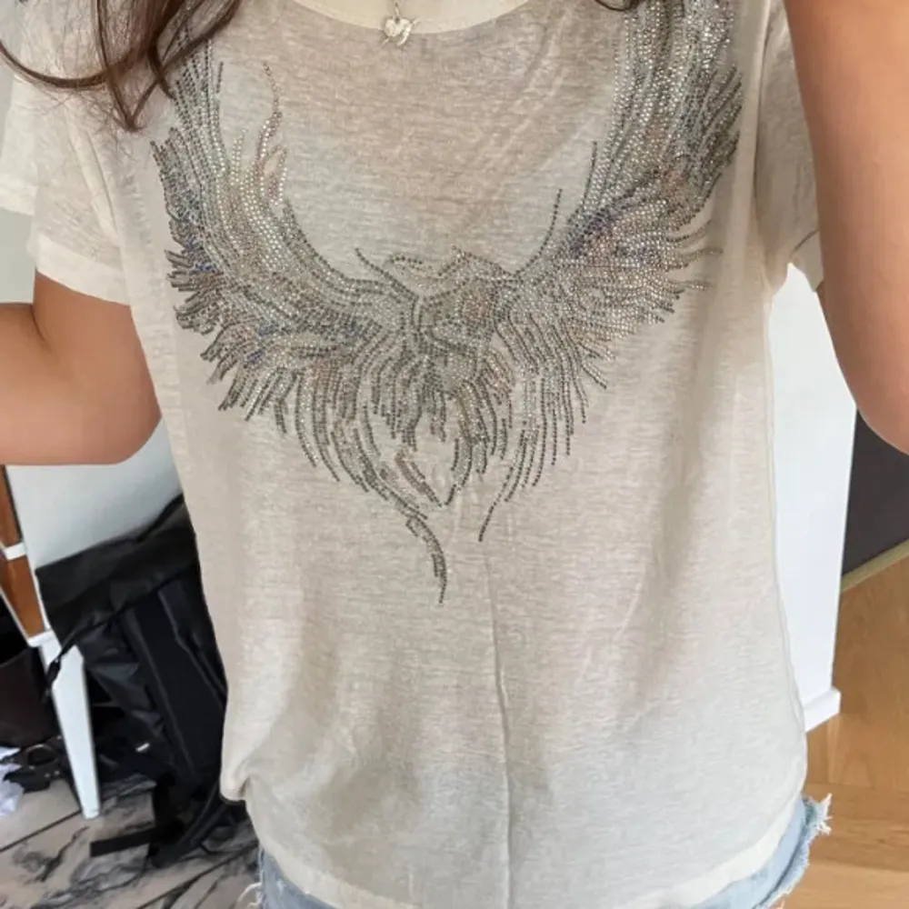 Säljer en snygg vit t-shirt från Zadig & Voltaire i storlek M. Endast andvänd ett fåtal gånger och alla diamanter är kvar. Finns inte att köpa längre. Modellen heter ”Marta Crystal Eagle Graphic Tee”. Pris kan diskuteras! Vid fler frågor eller i behov av fler bilder är det bara att skriva! Mvh Amanda.. T-shirts.