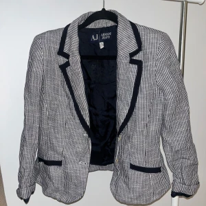 Randig kavaj från Armani Jeans - Snygg randig kavaj från Armani Jeans i svart och vit. Kavajen har en klassisk design med knappar och fickor fram. Perfekt för en stilren look.