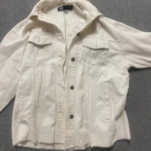 Vit manchesterjacka från Zara - Säljer en stilren vit/beige manchesterjacka från Zara. Jackan har knappar framtill och två bröstfickor med lock. Perfekt för en avslappnad look. Storlek xs men är oversize så passar xs-m beroende på hur man vill att den ska sitta 