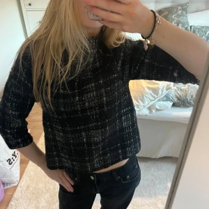 Svart och vit rutig topp - Säljer en snygg svart och vit rutig topp med trekvartsärm. Toppen har en croppad passform och är perfekt för en stilren look. Passar bra till både jeans och kjol.
