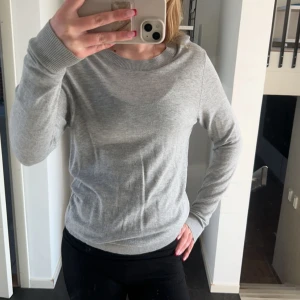 Grå stickad tröja - Säljer en stilren och bekväm grå stickad tröja. Perfekt för både vardag och mysiga stunder. Tröjan har långa ärmar och en rund halsringning. Passar bra till jeans.