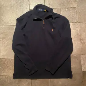 Säljer en snygg mörkblå Half zip från Polo Ralph Lauren i storlek L. Tröjan har en dragkedja vid halsen och det klassiska broderade logotypen på bröstet. Perfekt för både höst och vinter, och den är i mycket bra skick. Passar till både vardag och lite finare tillfällen. 