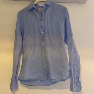 Ljusblå linne-skjorta från Bläck - Säljer en stilren ljusblå skjorta från Bläck. Köpte den i somras, men säljer den då den inte kommer till användning längre. Använd ytterst lite, ca 4 gånger och finns inga defekter eller tecken på användning! Nypris runt 900.