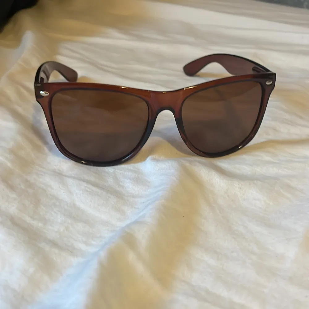 Snygga bruna solglasögon från Ray-Ban i mycket bra skick. De har en klassisk design med bruna bågar och mörka linser, perfekt för både vår och sommar. Passar lika bra till stranden som till en utekväll. Ett måste för den stilmedvetna!. Accessoarer.