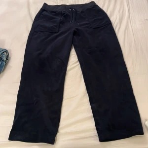 Svarta mjukisbyxor från Juicy Couture - Säljer ett par svarta mjukisbyxor från Juicy Couture i storlek S. Byxorna har en loose passform med snörning i midjan och praktiska fickor både fram och bak. Perfekta för en avslappnad dag hemma eller en snabb tur på stan. Superbekväma och stilrena!