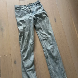 Grå jeans från ASOS - Säljer ett par ljusblå jeans från ASOS i denim/tall. De har en klassisk design med knapp och dragkedja framtill. Perfekta för en avslappnad stil.