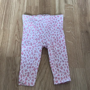 Rosa leopardmönstrade leggings från Lupilu - Säljer ett par söta rosa leggings med leopardmönster från Lupilu. Perfekta för små barn som vill ha något bekvämt och stiligt. Tillverkade i mjukt material för extra komfort.