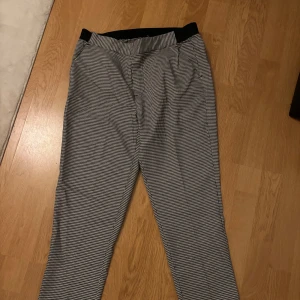 Svartvit rutig byxa med hög midja - Snygga svartvita rutiga byxor med hög midja och rak passform. Perfekta för en stilren look. Byxorna har en klassisk design med en bekväm midja. Säljer de i två storlekar, storlek 38 och 40. Aldrig använt alla lappar är kvar. 