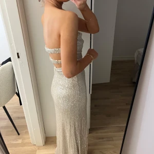 Balklänning - axelbandslös långklänning i glittrande champagne. Säljer då jag tänkt ha som balklänning men hittat en annan. Den är helt ny med lappen kvar. Jag är 163 och skulle säga att den är perfekt längd för mig. Pris kan diskuteras 🤍