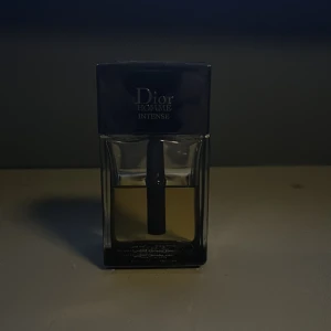 Dior Homme Intense - Dior Homme Intense är en elegant herrparfym med en rik och djup doftprofil. Den har noter av iris, trä, puder och jordiga toner, kompletterat med inslag av viol, aromatiska och blommiga accenter. Flaskan är stilren med en mörk topp och en gyllene vätska. Ca 60ml kvar.