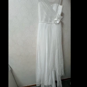 Vit klänning från Milo Kids - Superfin vit klänning från Milo Kids med en stor rosett framtill. Klänningen har ett prickigt mönster och är axelbandslös med en smockad överdel. Perfekt för sommarens fester eller speciella tillfällen. Tillverkad i Turkiet och rekommenderas att kemtvättas. Priset kan diskuteras. 